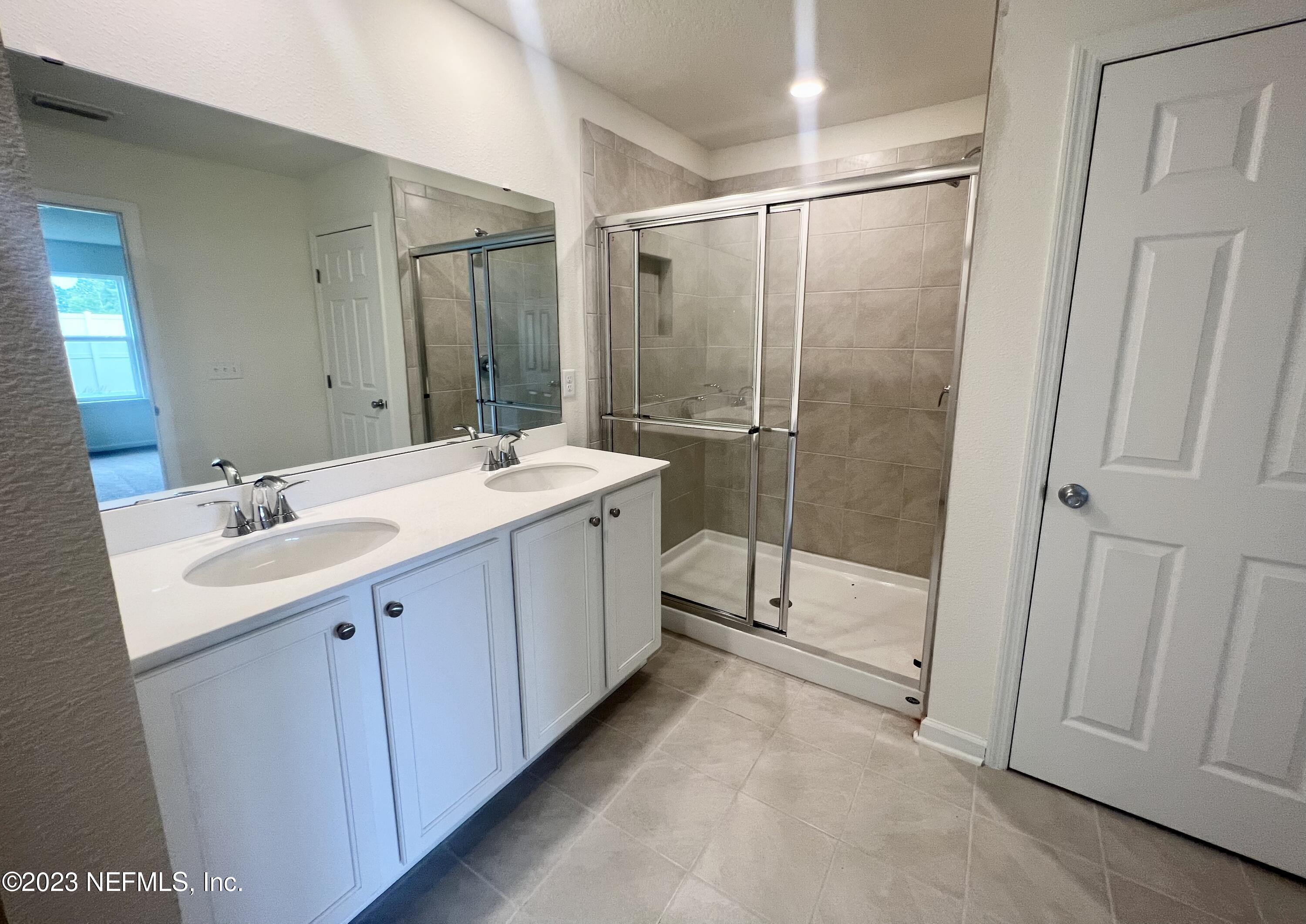 7954 Rippa Valley Way Jacksonville, FL 32222 - Photo 2 of 9 a bathroom with a double vanity sink mirror and shower