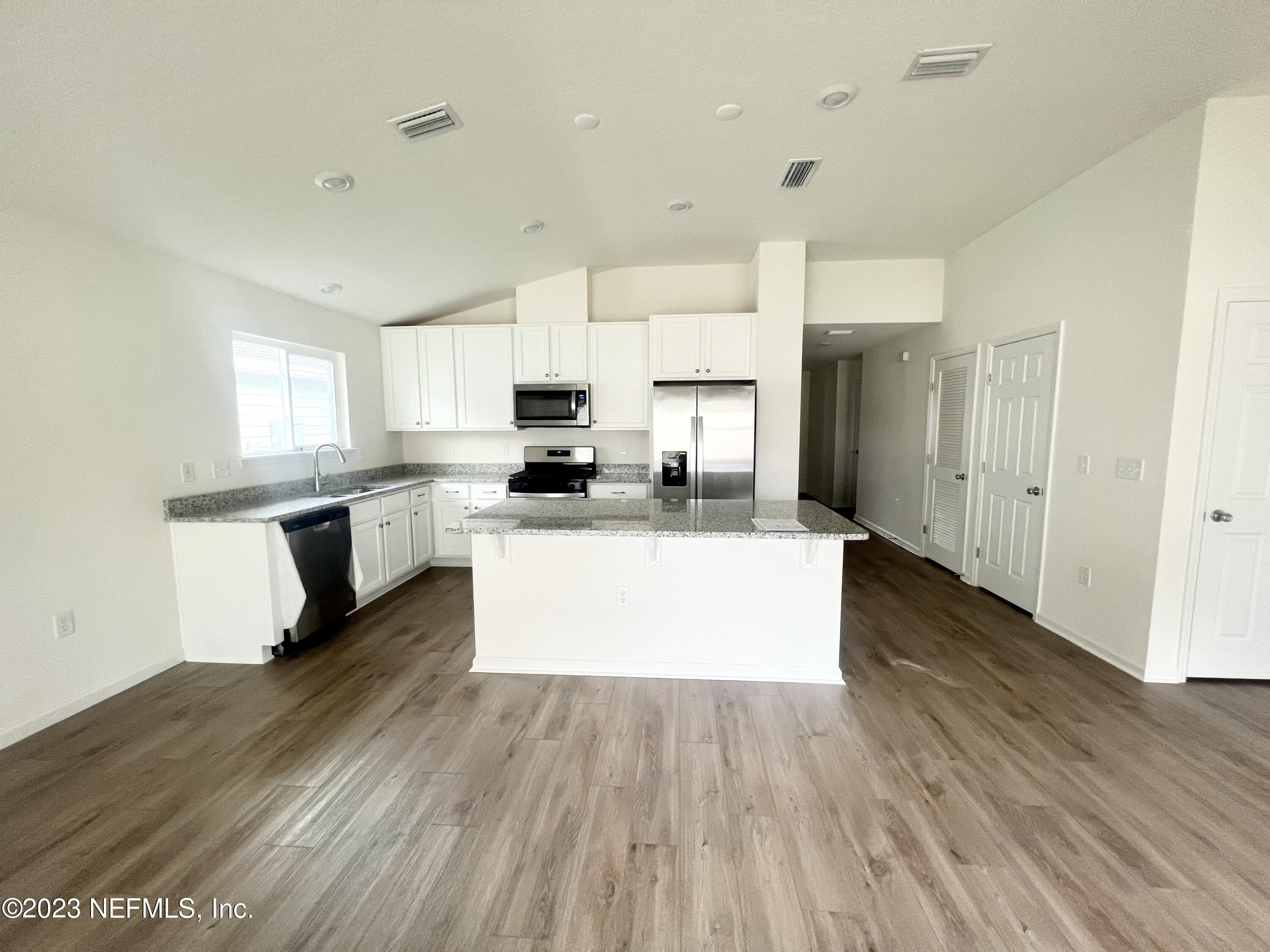 7954 Rippa Valley Way Jacksonville, FL 32222 - Photo 5 of 9 a large kitchen with cabinets wooden floor and stainless steel appliances