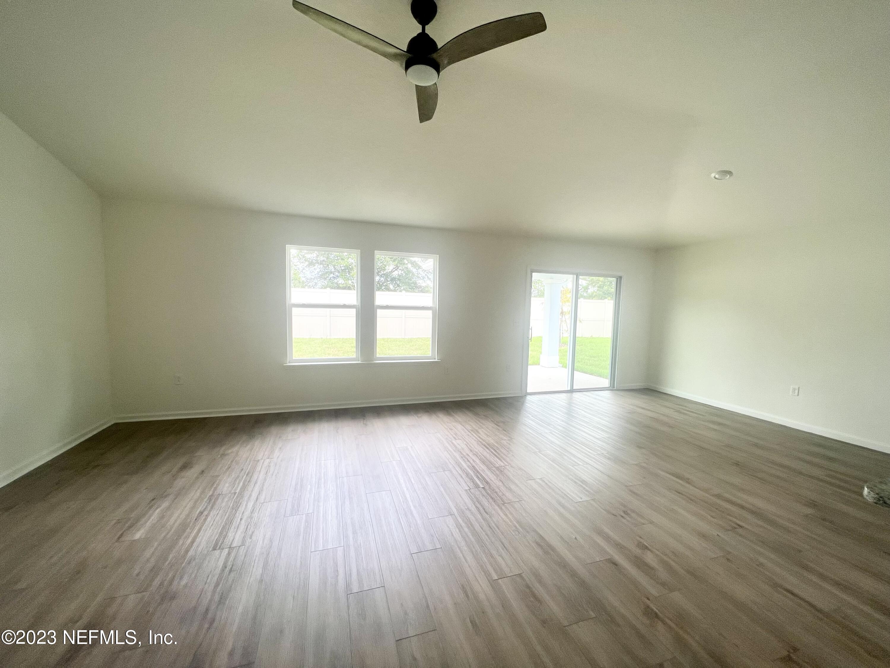 7954 Rippa Valley Way Jacksonville, FL 32222 - Photo 6 of 9 an empty room with wooden floor and windows
