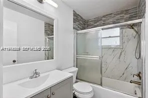 a bathroom with a shower sink vanity mirror and toilet