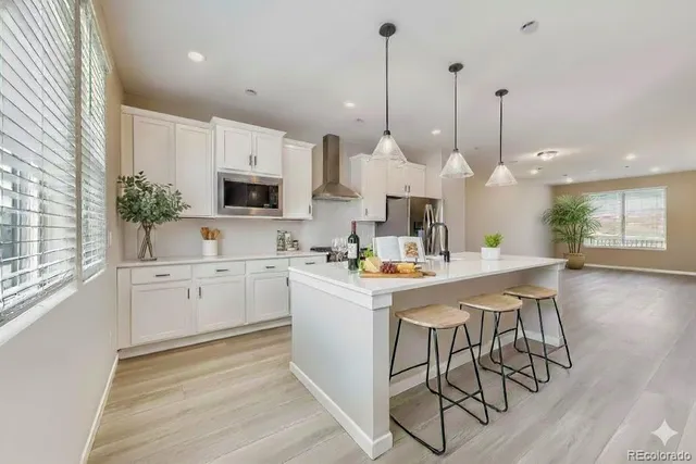 a kitchen with stainless steel appliances kitchen island granite countertop a stove a sink and white cabinets with wooden floor