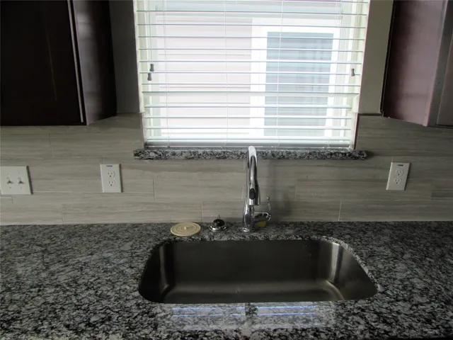 a bathroom with a granite countertop sink a window and bathtub