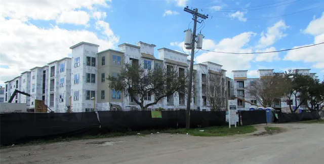 a street view with tall buildings and a yard