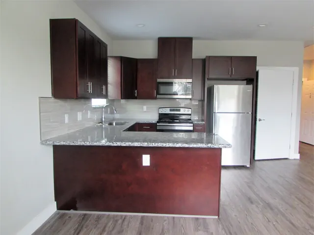 a kitchen with kitchen island granite countertop a sink stove and refrigerator