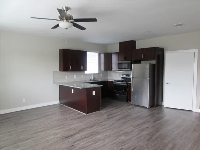 a kitchen with stainless steel appliances granite countertop a refrigerator a stove top oven a sink and dishwasher with wooden floor