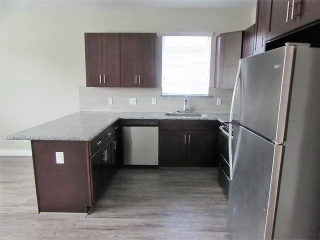 a kitchen with stainless steel appliances granite countertop a refrigerator a sink a stove and a refrigerator