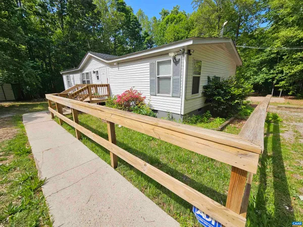 a view of house with wooden deck and yard