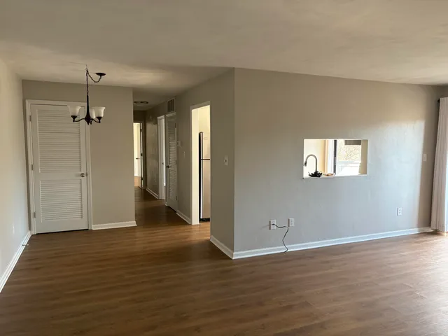 an empty room with wooden floor a ceiling fan and windows