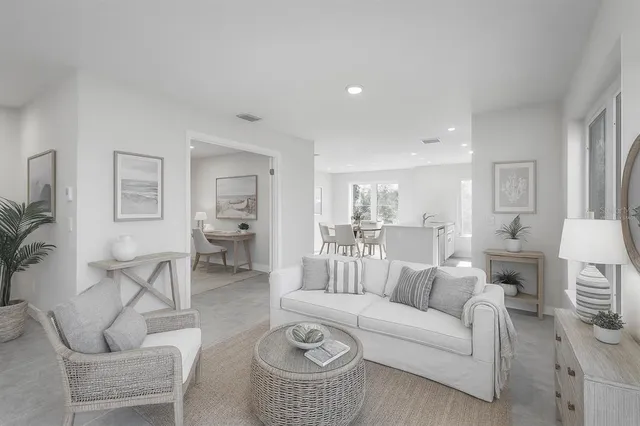 a living room with furniture a rug kitchen view and a table
