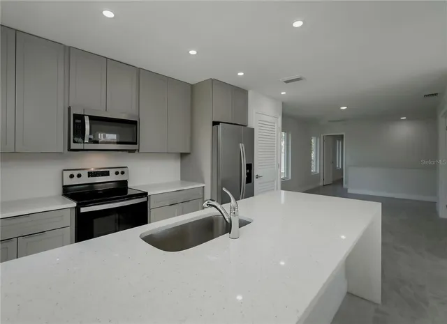a view of kitchen with stainless steel appliances wooden floor and window
