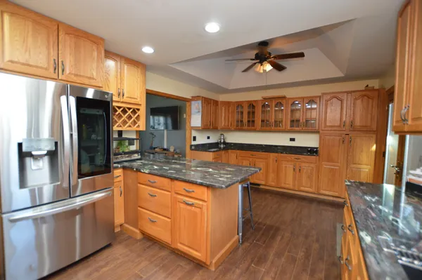a kitchen with stainless steel appliances granite countertop a refrigerator a sink dishwasher a stove and white countertops with wooden floor