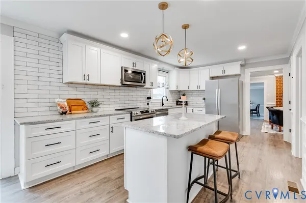 a kitchen with stainless steel appliances granite countertop a sink a stove a refrigerator cabinets and chairs