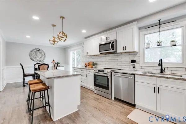 a open kitchen with stainless steel appliances granite countertop a sink and stove top oven with wooden floor