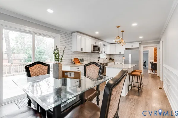 a kitchen with stainless steel appliances granite countertop a table chairs refrigerator and microwave