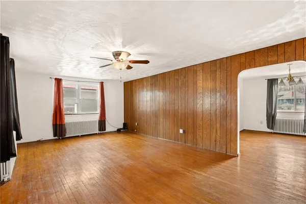 a view of an empty room with window and wooden floor
