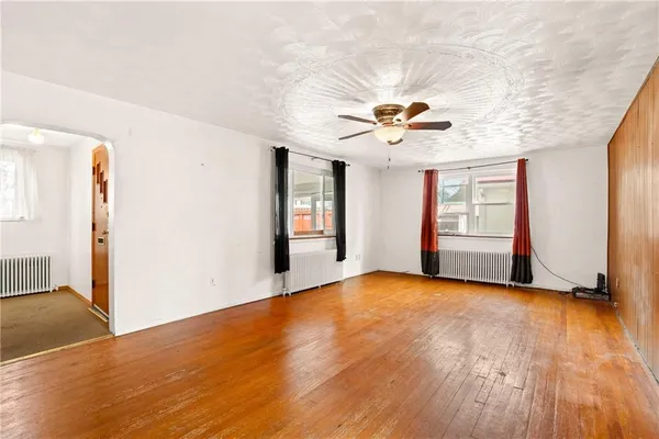 a view of an empty room with window and wooden floor