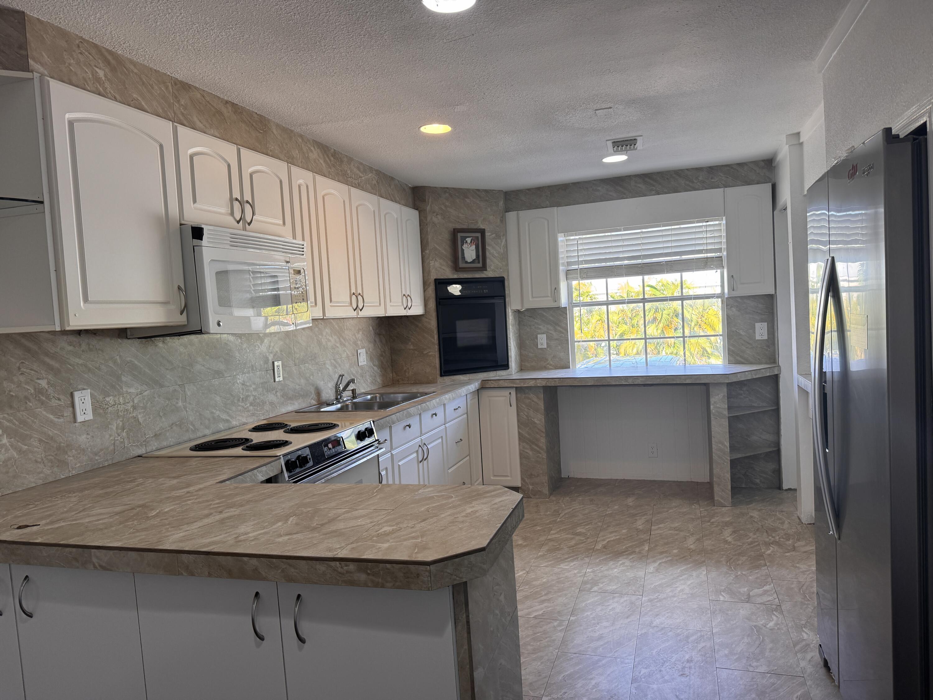 969 Plantation Road Key Largo, FL 33037 - Photo 2 of 26 a kitchen with granite countertop a stove a sink and a refrigerator