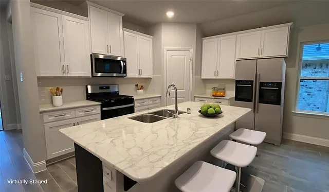 a kitchen with stainless steel appliances kitchen island granite countertop a kitchen island a stove a sink a microwave and dining table