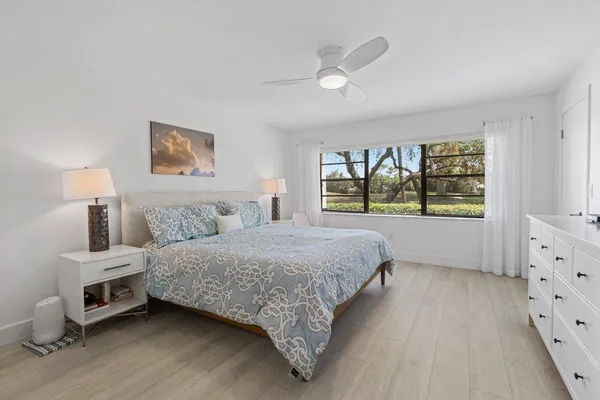 a spacious bedroom with a bed and a lamp on dresser