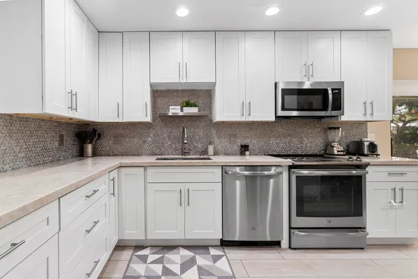 a kitchen with cabinets stainless steel appliances and wooden floor