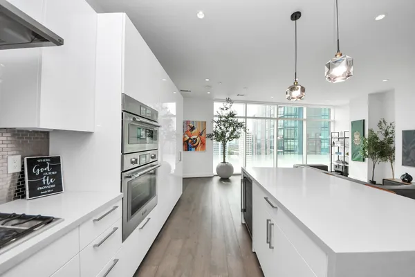 a large kitchen with kitchen island a large window a sink and stainless steel appliances