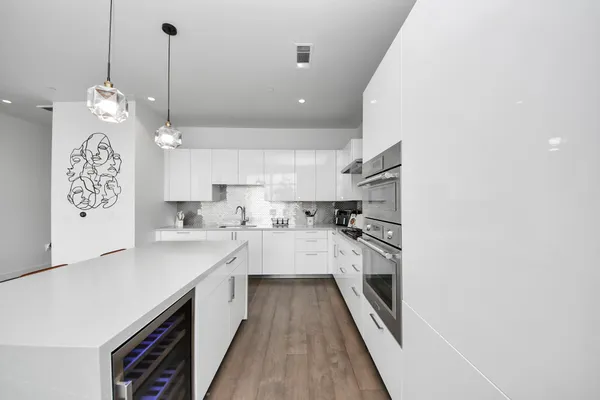 a large kitchen with granite countertop a large kitchen island white cabinets and stainless steel appliances