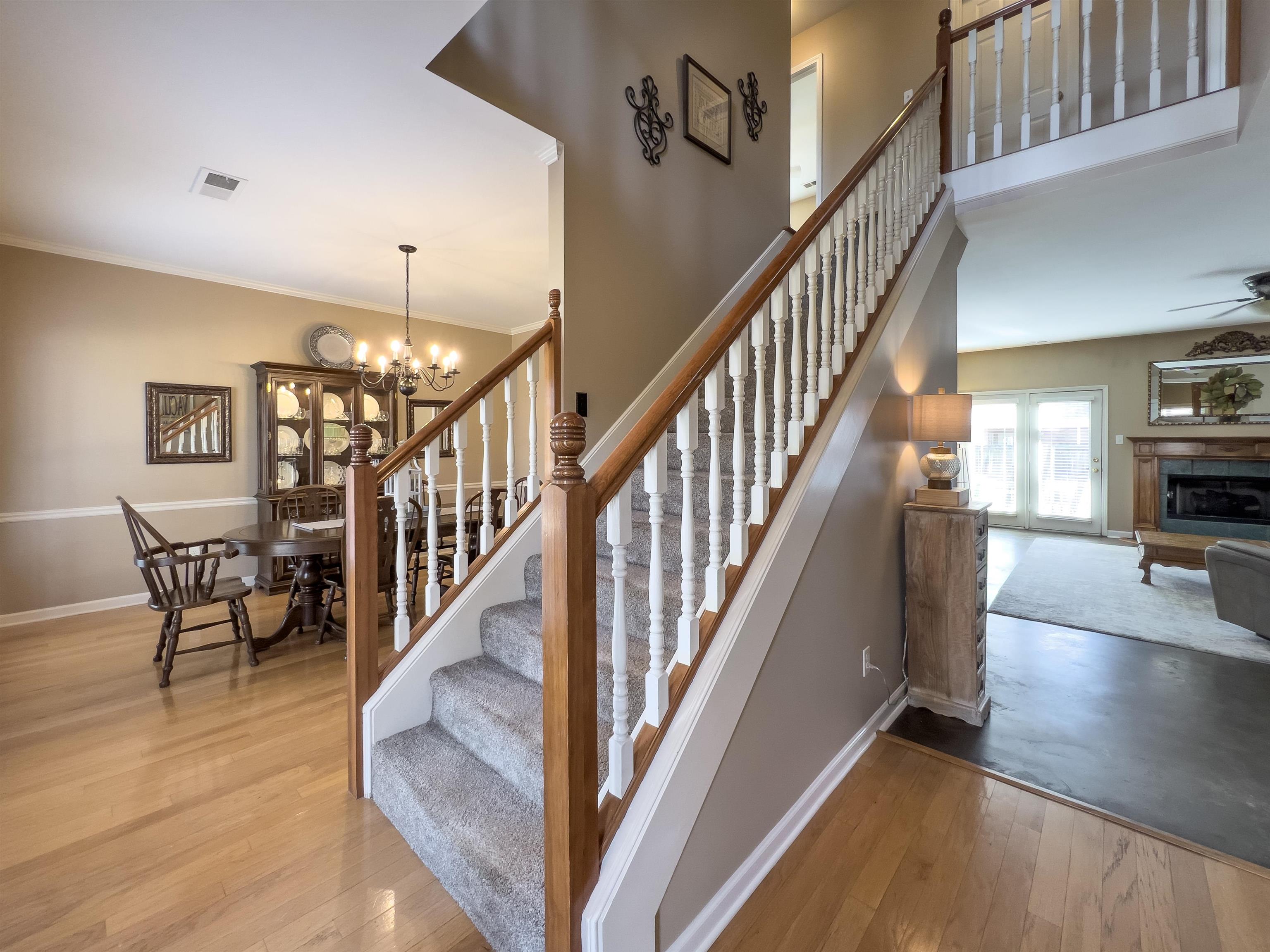 747 Steeple Ridge Cove Collierville, TN 38017 - Photo 3 of 39 a view of staircase and dining room with wooden floor and a chandelier