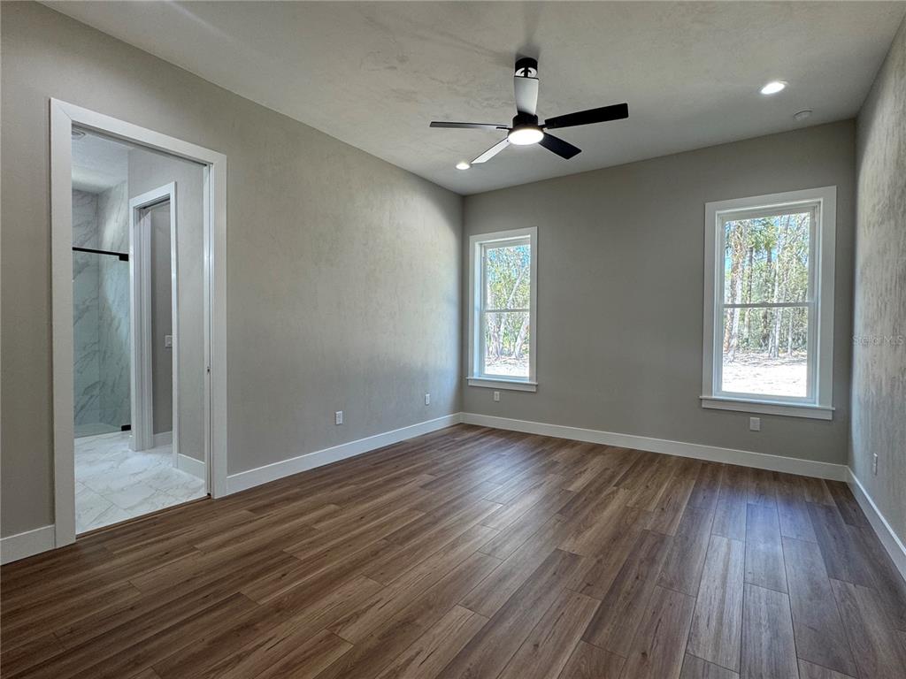 5151 Northwest 73rd Street Chiefland, FL 32626 - Photo 38 of 58 an empty room with wooden floor a ceiling fan and windows