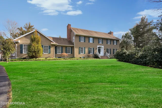 a front view of a house with garden and trees