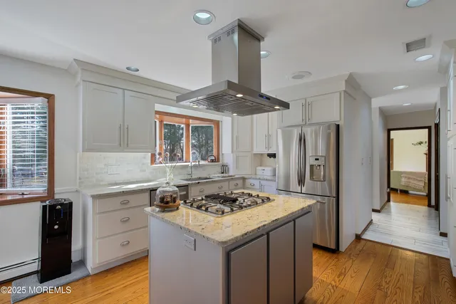 a kitchen with granite countertop a sink stainless steel appliances and white cabinets