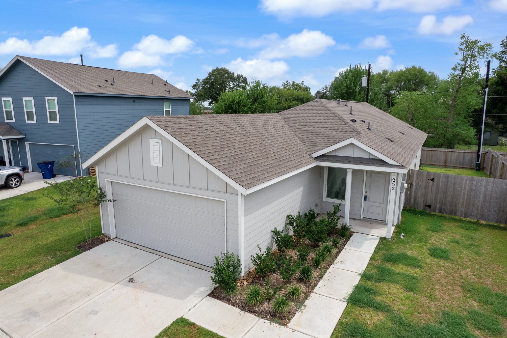 252 Houston Street Angleton, TX 77515 - Photo 36 of 49 Elevated exterior view showcases the home’s single-story design, two-car garage, covered front entry, and landscaped walkway.