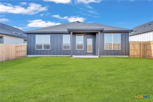 a brick house next to a yard with a large tree