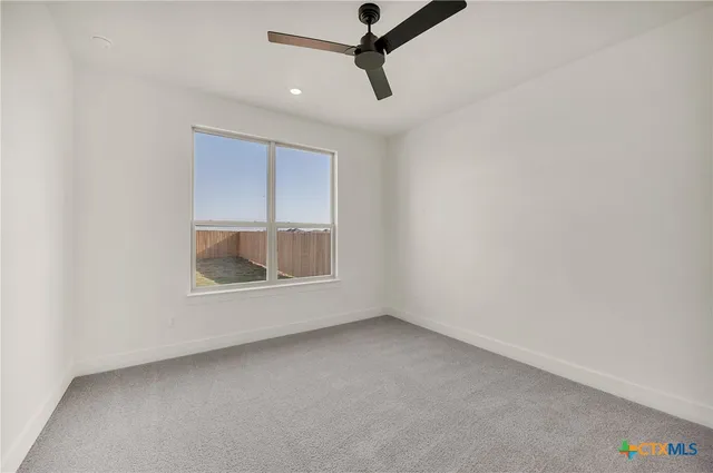 an empty room with a window and ceiling fan
