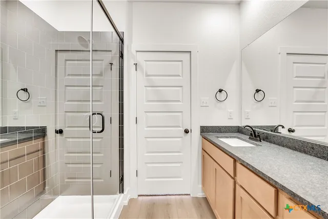 a bathroom with a granite countertop sink a mirror and a shower