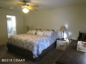 99 Mayfield Circle Ormond Beach, FL 32174 - Photo 13 of 28 a bedroom with a bed and a chandelier
