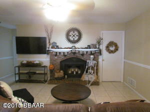 99 Mayfield Circle Ormond Beach, FL 32174 - Photo 8 of 28 a living room with furniture a flat screen tv and a fireplace