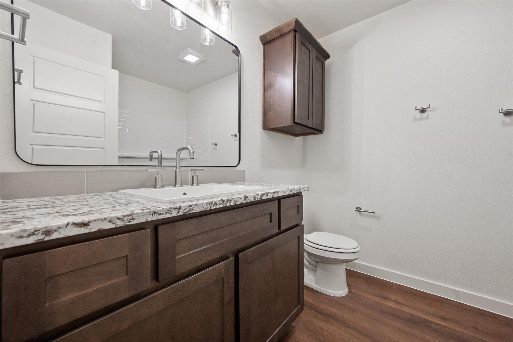7207 7th Street Lubbock, TX 79416 - Photo 18 of 22 a bathroom with a granite countertop toilet sink and mirror