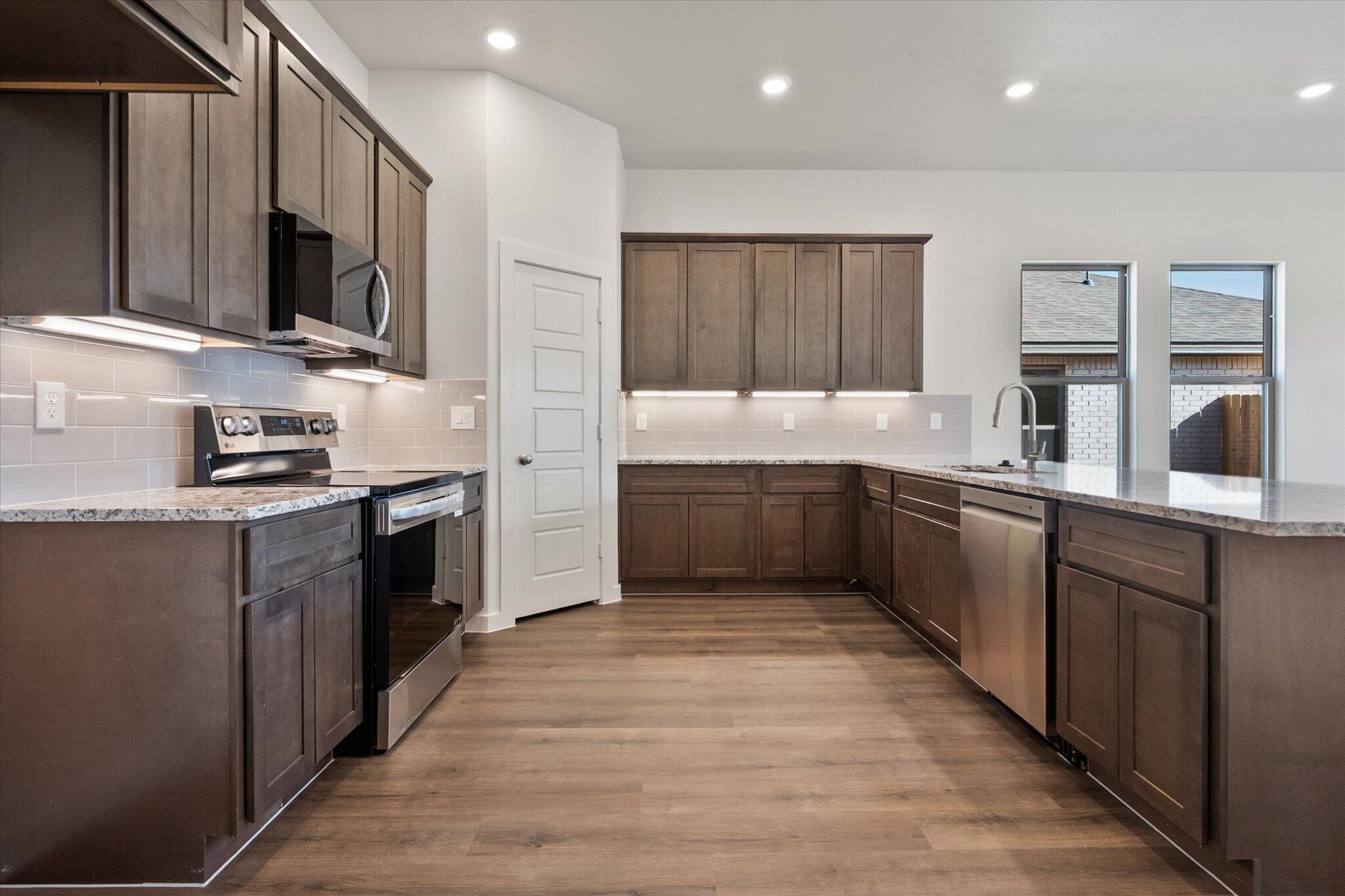 7207 7th Street Lubbock, TX 79416 - Photo 4 of 22 a kitchen with stainless steel appliances a sink wooden cabinets and a counter top space