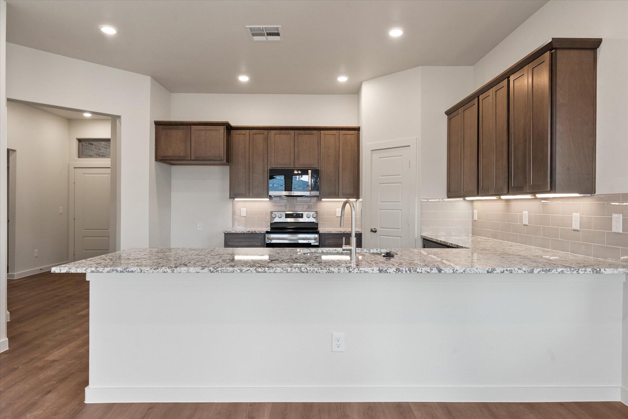 7207 7th Street Lubbock, TX 79416 - Photo 6 of 22 a kitchen with stainless steel appliances granite countertop a sink a stove and a refrigerator