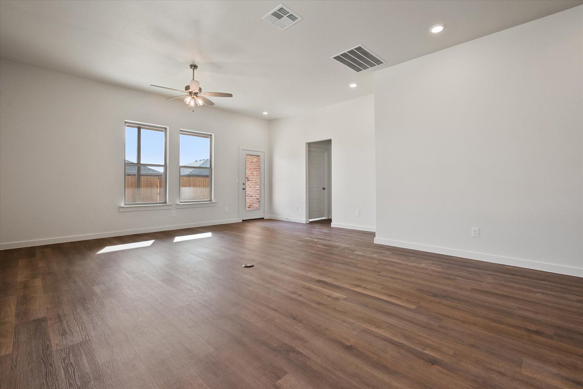 7207 7th Street Lubbock, TX 79416 - Photo 8 of 22 an empty room with wooden floor chandelier fan and windows