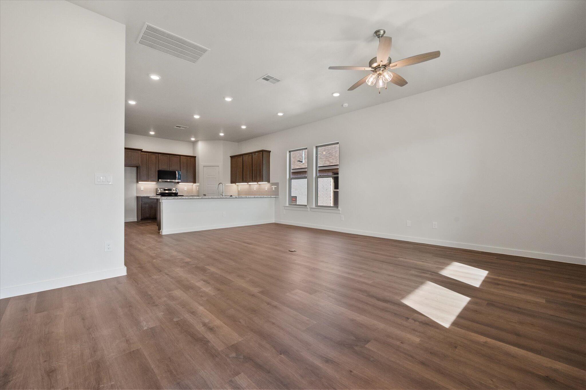 7207 7th Street Lubbock, TX 79416 - Photo 10 of 22 a view of an empty room with wooden floor and a kitchen