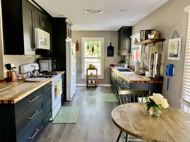 a kitchen with stainless steel appliances stove refrigerator dining table and chairs