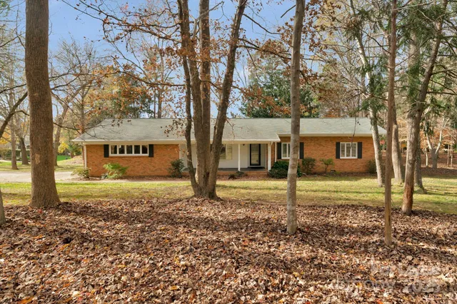 a view of a house with a yard and large tree