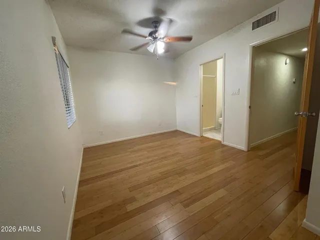 an empty room with wooden floor cabinet and windows