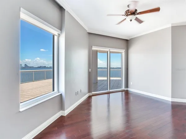 an empty room with wooden floor and windows