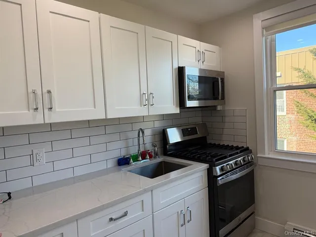 a kitchen with granite countertop white cabinets and a stove