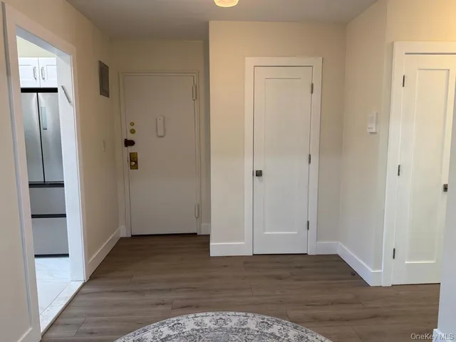 a view of an empty room with wooden floor and a bathroom