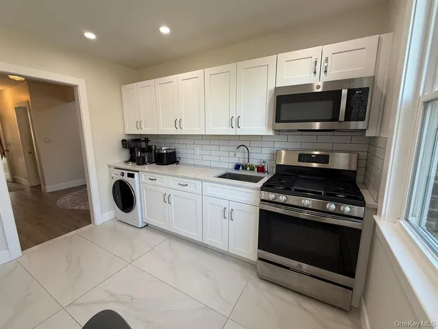 a kitchen with a stove a microwave and white cabinets