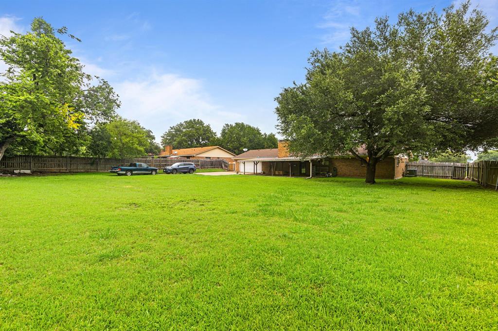 505 Pinewood Lane Hewitt, TX 76643 - Photo 29 of 38 Expansive backyard featuring a lush green lawn, mature shade trees, and privacy fencing