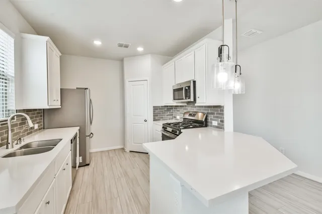 a kitchen with cabinets stainless steel appliances and wooden floor